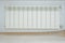 Just installed a new steel heating radiator. Full view of a white radiator against a cream wall . Interior detail. White metal