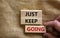 Just keep going symbol. Wooden blocks with words `Just keep going`. Beautiful canvas background, businessman hand. Business, jus