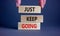 Just keep going symbol. Wooden blocks with words `Just keep going`. Beautiful grey background, businessman hand. Business, just