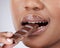 Just a little bite...Cropped studio shot of an unrecognizable woman eating a slab of chocolate against a grey background