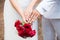 Just married couple compare their wedding rings while holding each others` hands and a bouquet.