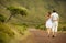 Just married couple in honneymoon walking along countriside road on, view from back