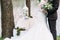 Just married couple hugs outdoor with bouquet