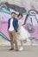 Just married loving hipster couple in wedding dress and suit outdoor in city setting against colorful graffiti wall.