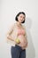 Just one apple a day. Beautiful young pregnant woman with smile and holding green apple while standing at white background