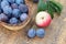 Just picked plums in wicker basket and apple on old wooden boards outdoor