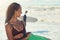 Just smile and wave. a woman at the beach with her surfboard while a male surfer stands in the background.