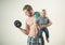 Just sport. Strong man with dumbbells hold baby boy. Father build biceps triceps with son. Father and child training