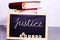 JUSTICE WRITTEN ON CHALKBOARD WITH LAWBOOKS AND WHITE BACKGROUND