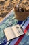 Jute beach bag, wireless headphones, notepad and sunglasses on the striped towel on the sand.