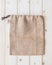 Jute hessian canvas tote bag with drawstring, mockup of small eco sack made from natural hemp burlap flat lay on white wood