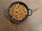 Kacang bawang or garlic flavored fried peanuts placed in a frying pan isolated on wooden board background. High angle view.