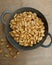 Kacang bawang or garlic flavored fried peanuts placed in a frying pan isolated on wooden board background. High angle view.