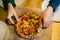 Kad hands holding round pizza with basil pesto sauce