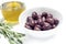 Kalamata black olives in a white bowl and olive oil, rosemary ga