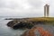 Kalfshamarsvik lighthouse in the western part of Iceland during rainy weather. Ocean view from the beach with basalt rocks and tar