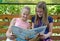 KALININGRAD, RUSSIA. Two girls girlfriends with a smile consider the book on a bench. The Russian text - Gulliver`s Travels