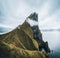 Kalsoy Island with Kallur lighthouse on on Faroe islands, Denmark, Europe. Clouds over high cliffs, turquoise Atlantic