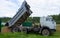 A KAMAZ truck with sand is parked on a country road near a fence.