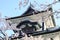 Kanazawa castle top roof, Japanese traditional castle roof, soft bright pink sakura branch in front old castle on blue sky backgro