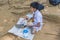 Kandy, Sri Lanka: 03/19/2019: Peradeniya Botanical Gardens small school boy seated eating traditional lunch of rice