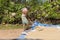 Kandy, Sri Lanka: 03/20/2019: Rice farmer raking rice crop to dry in the sun