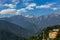 Kangchenjunga mountain with clouds above and green roof house. Among green hills that view in the evening in North Sikkim, India