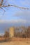 Kansas farm silo with prairie grass, tree`s, blue sky and clouds out in the country.