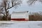 Kansas Red Barn with Snow out in the country that`s bright and colorful with blue Sky.