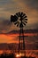 Kansas Windmill silhouette with a colorful Sunset with clouds and the sun out in the country.