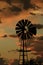 Kansas Windmill sunset with a tree silhouette and clouds that\\\'s bright and colorful