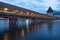 KapellbrÃ¼cke, medieval bridge in Luzern at night. The bridge is illuminated, the lights are reflected in the lake