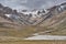 Karakoram mountain landscape. Volcanic stone as well as weather-ground limestone. Snowy peaks and green mountain passes crossed by