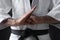 Karate coach wearing kimono and black belt on dark background, closeup