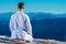 Karate master meditating on top of a mountain wearing kimono while looking down at the mountain lake