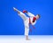 Karateka is training kick leg on a blue background