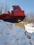 Karelian red tractor is behind a snowy mountain