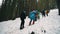 Karpaty, Hoverla, Ukraine - March 2023: A group of tourists with backpacks and raincoats climb a mountain in the middle