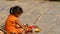 Kathmandu, Nepal - 8 October 2018 Side view of Little ethnic girl selling various religious attributes, sitting on stone