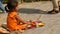 Kathmandu, Nepal - 8 October 2018 Side view of Little ethnic girl selling various religious attributes, sitting on stone