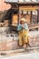 Kathmandu / Nepal - February 2016: Old poor barefoot woman in bright traditional clothes sitting on the sun on Kathmandu street