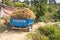 Kathmandu, Nepal - October 29, 2021: Truck overloaded with hay, on a dirt mountain road. Blue lorry on unpaved road in the