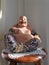 Katyayana Buddha statue sitting on teak wood table near wall in home closeup with the sun shining in.