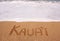 Kauai written into the sand in surging tide