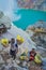 KAWEH IJEN, INDONESIA - 3 MARCH, 2017: Local miners carrying heavy baskets of yellow sulfur rocks up mountain side