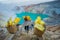 KAWEH IJEN, INDONESIA - 3 MARCH, 2017: Local miners carrying heavy baskets of yellow sulfur rocks up mountain side