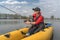 Kayak fishing at lake. Fisherwoman on inflatable boat with fishing tackle