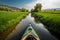 a kayak floats along a narrow meadow river Generative AI