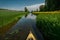 a kayak floats along a narrow meadow river Generative AI