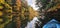 Kayak on mirror Lake with fall leaves changing to orange and red in the early part of wisconsins season change